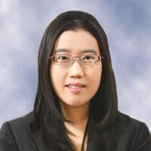 A woman with dark hair and glasses smiles at the camera 
