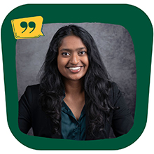 A woman in a black jacket and dark green shirt stands smiling